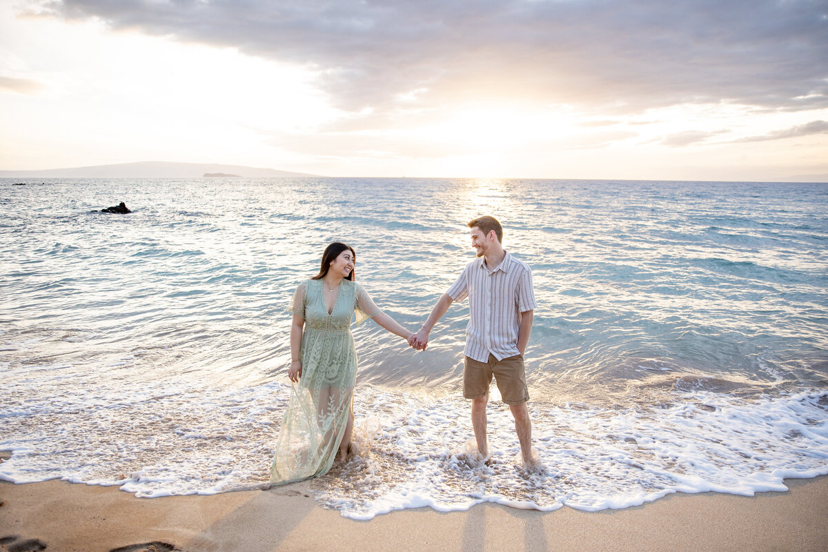 Hawaii Engagement Photographer captures couple holding hands in water during beach engagement photos