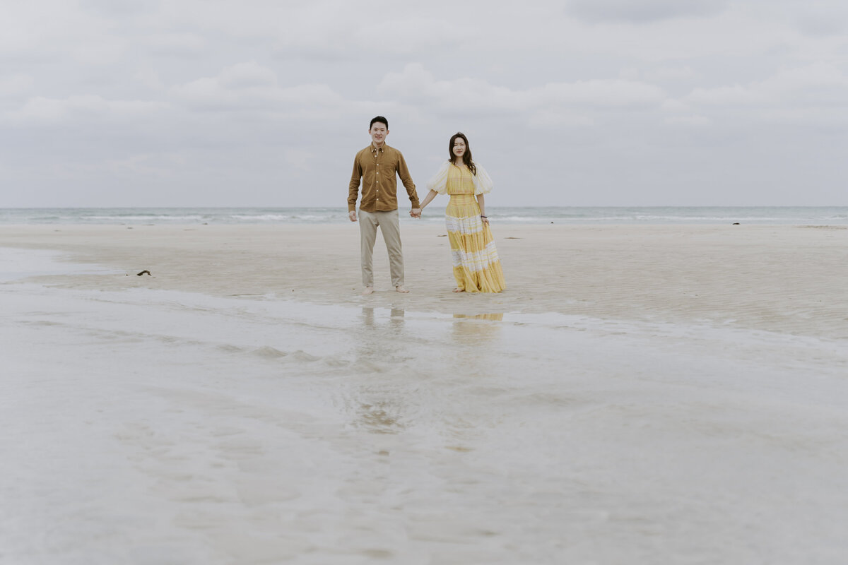 the couple holding each other's hands in the shore of jeju island south korea