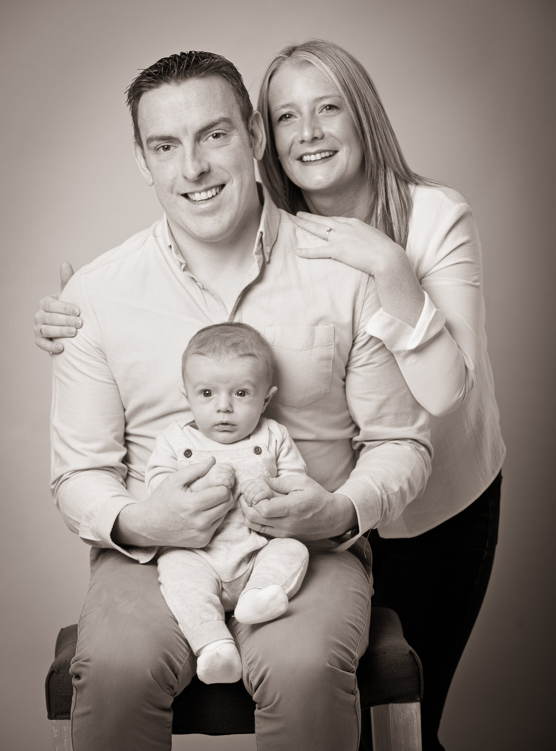 black & white portrait of a mother, father and baby smiling