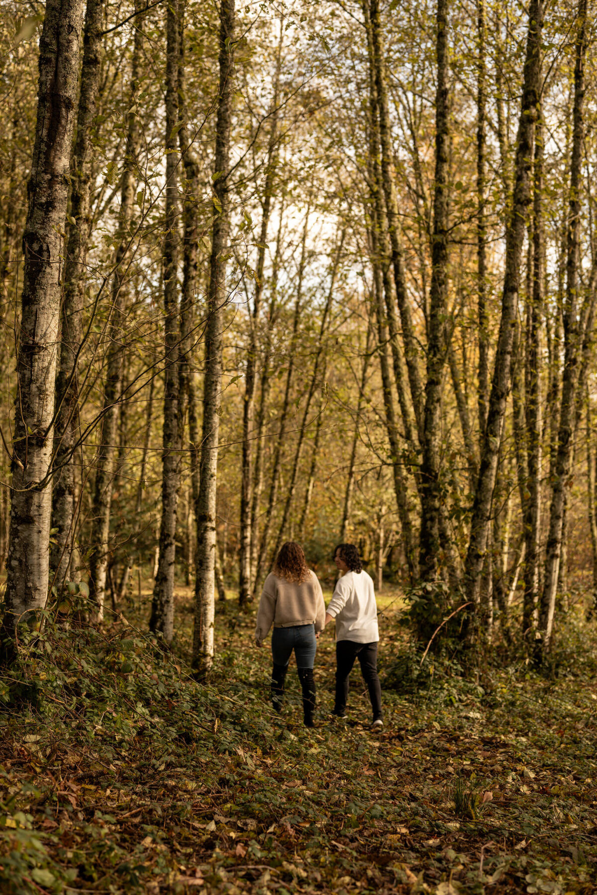 couple walking through a forest taken by photographers in idaho