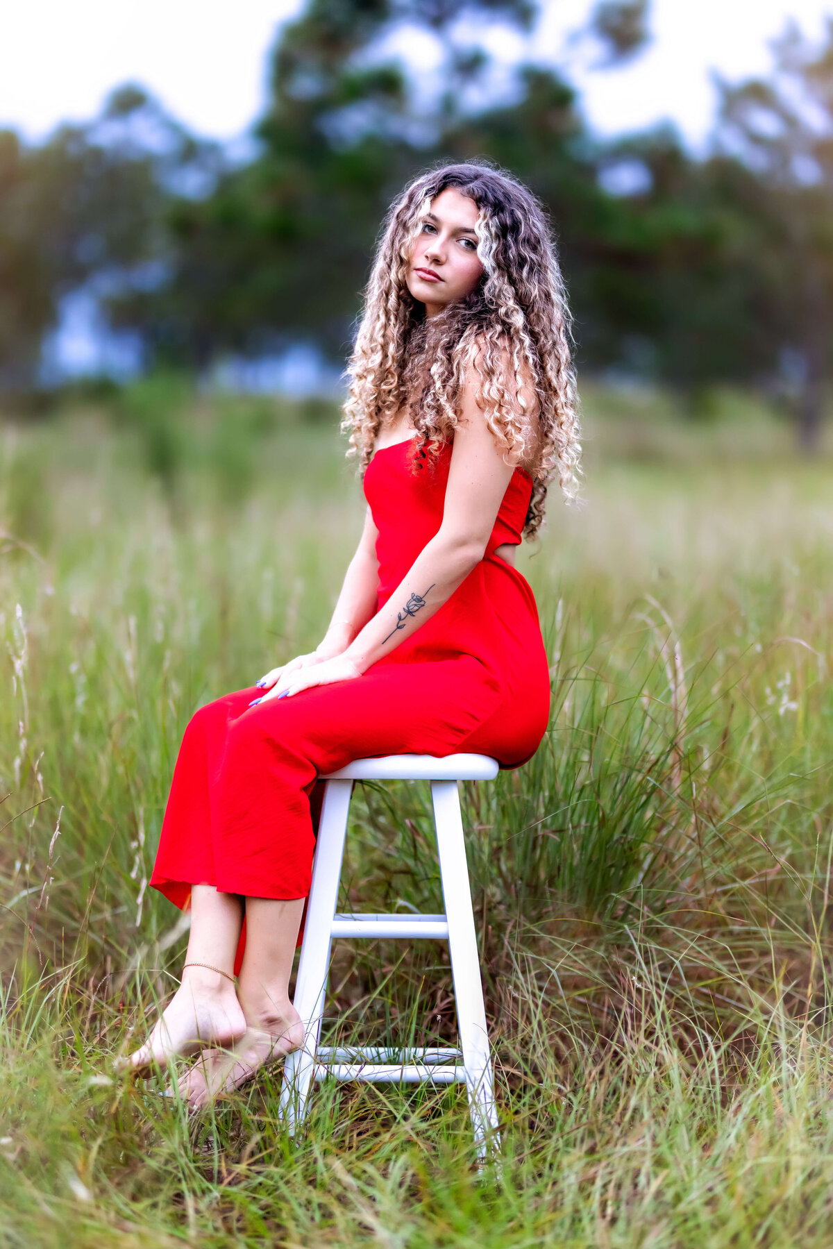 Senior girl posing on a rustic stool in an open field during her Orlando senior photography session.