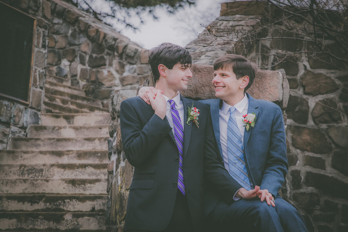 Grooms wrap their arms around each other on staircase.