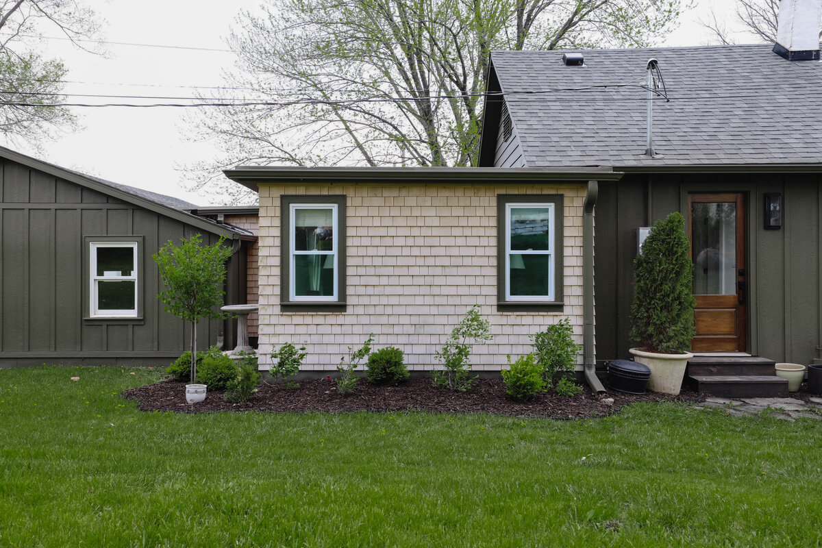 The exterior project by Nadine Stay. Board and batten siding install. Muddled Basil by Sherwin Williams exterior paint color. Flagstone path, brick front porch floor, and a custom built railing. Cabin exterior.