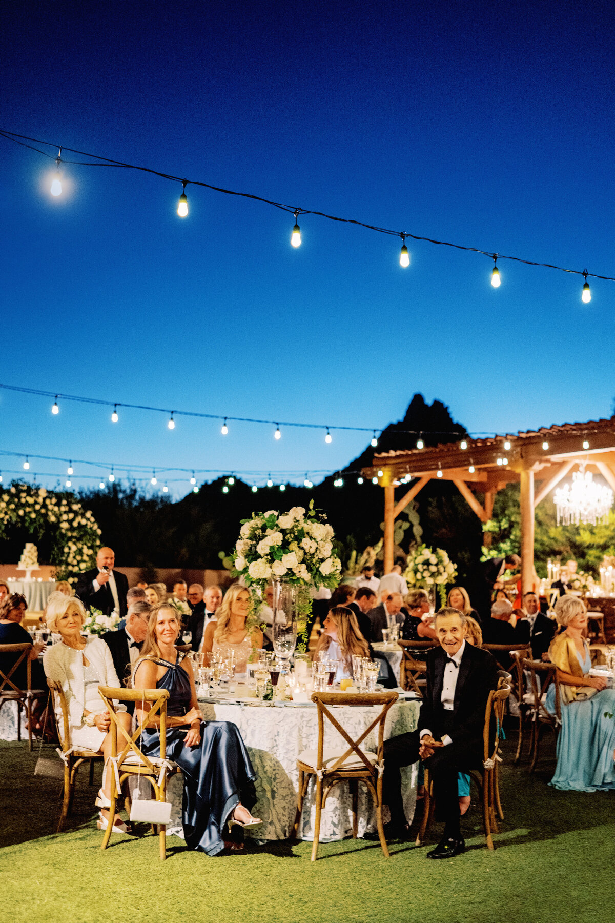 Wedding guests enjoy an elegant reception under twinkling string lights, creating an intimate and memorable atmosphere at a luxury desert wedding venue.