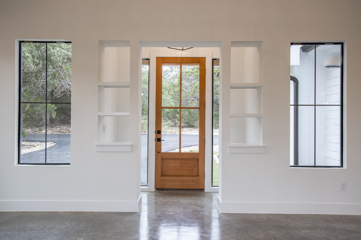 wood glass door in entry to home with built in shelves