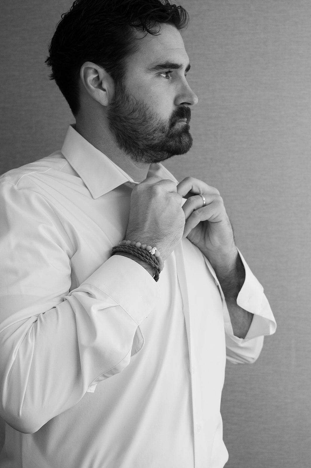 A man buttoning up a dress shirt as he prepares for his vow renewal planned by Perfect Thirds and Co.