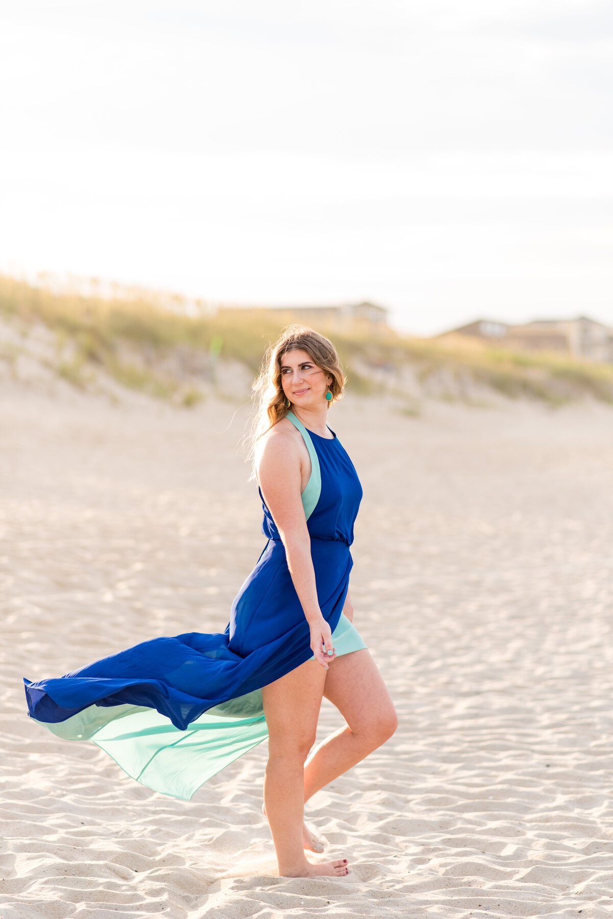 Mechanicsville high school senior girl wearing a long dress walks across beach in the Outer Banks during her portrait session.