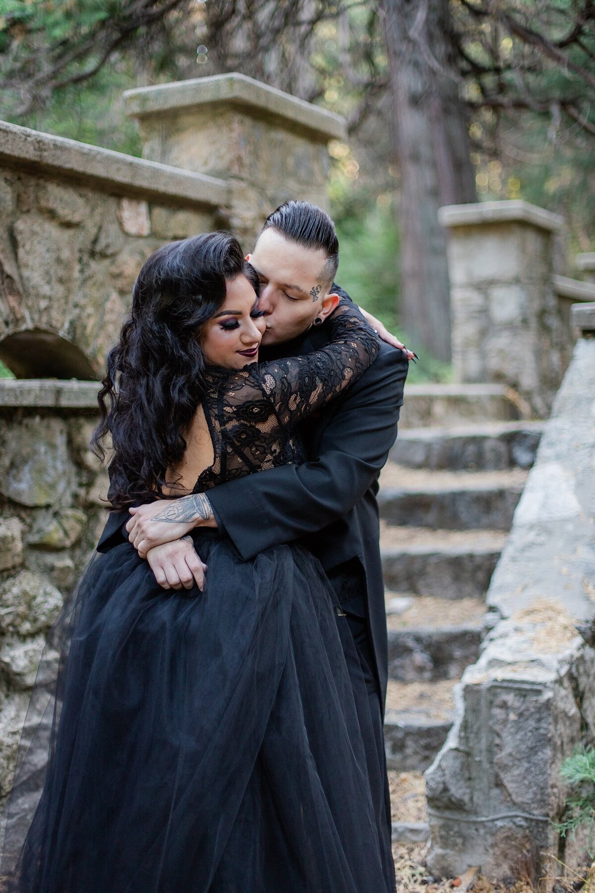 groom kisses bride in black wedding dress