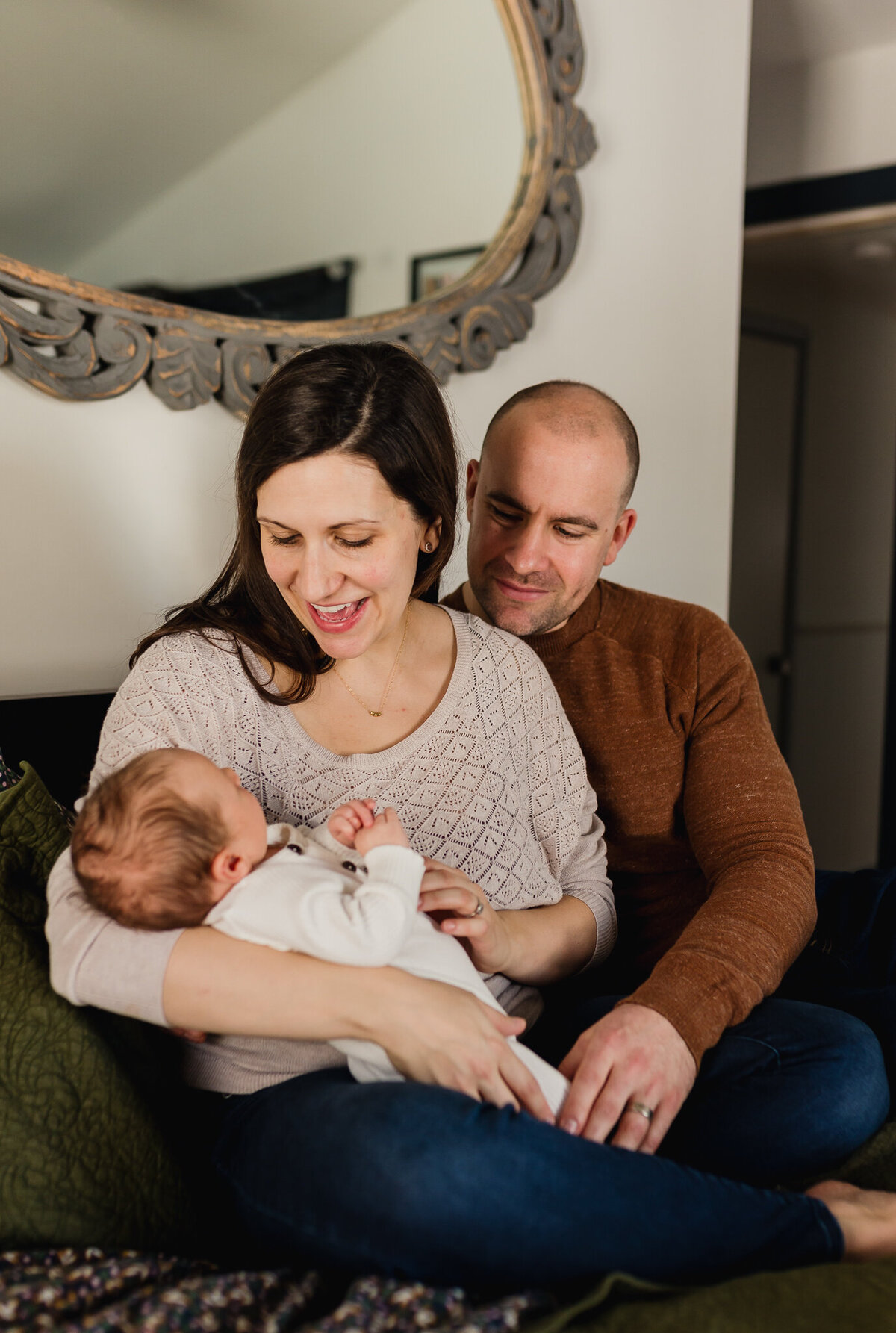 Infant photography of a mom holding new born baby, with dad holding arms around mom.
