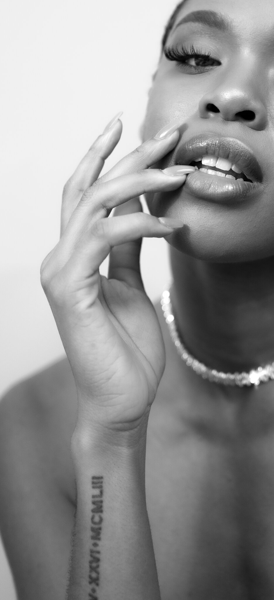 close up in black and white showcasing a woman manicured nails and white diamond necklace