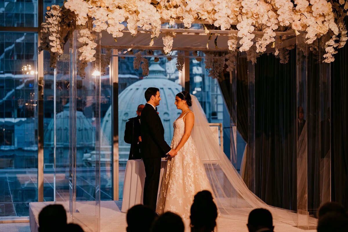 bride and groom getting married under clear lucite chuppah by Philadelphia wedding florist sebesta design