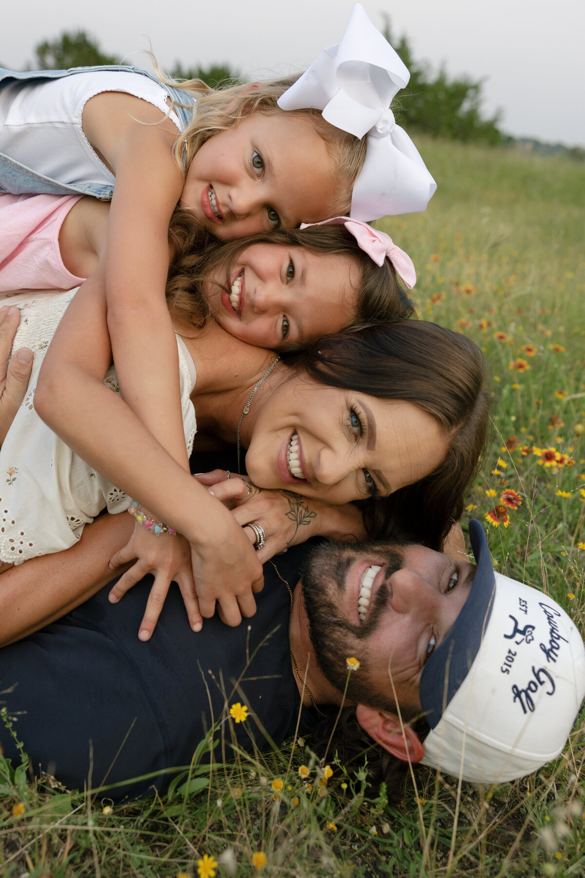 A family of four dog piled on each other laughing and smiling. 