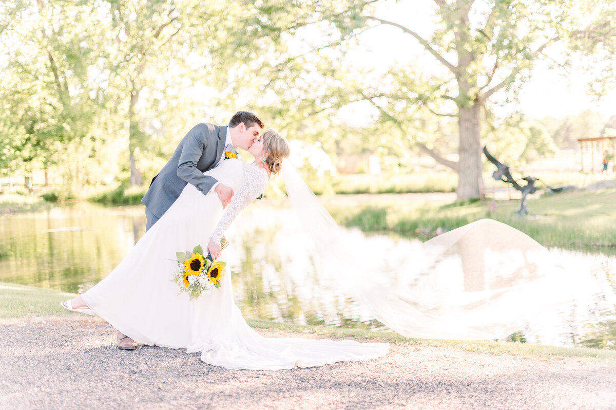 groom dipping bride during a colorado summer wedding while brides veil flys in wind