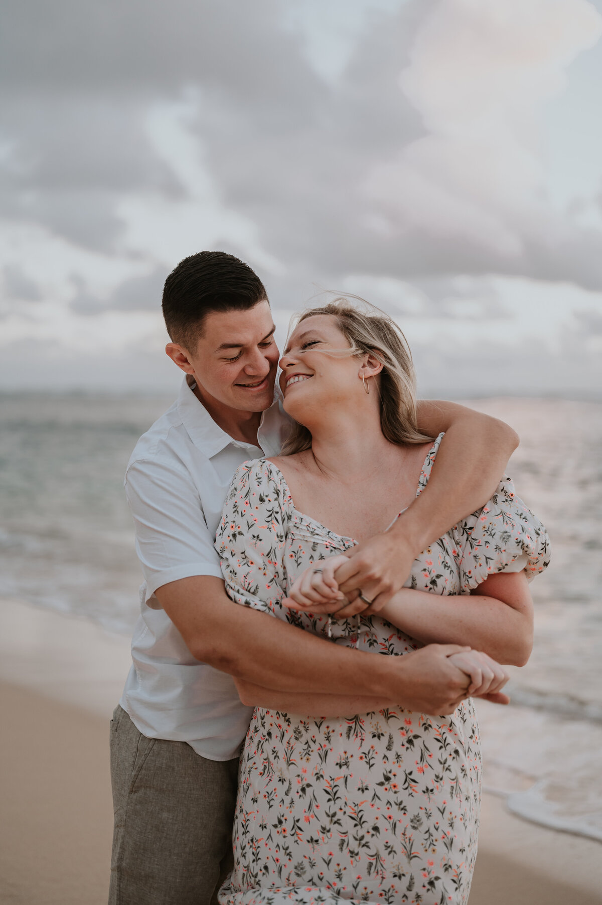 a couple who is recently engaged takes photos with their hawaii photographer at kahala beach at sunrise