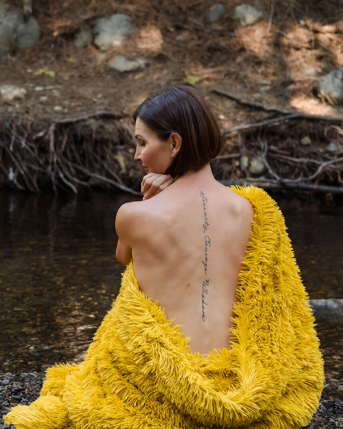 woman wearing yellow blanket on one shoulder with tattoo on back