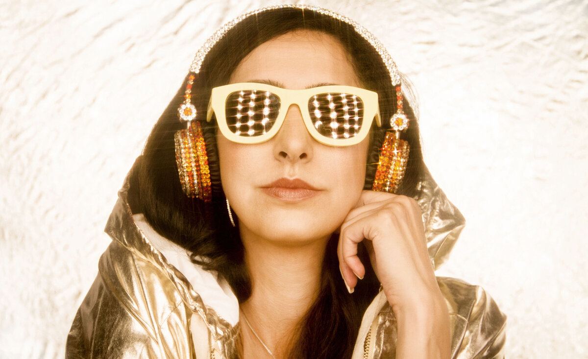 Female musician portrait Lana Zahia wearing gold hoodie headphones sunglasses  lights reflecting through lenes