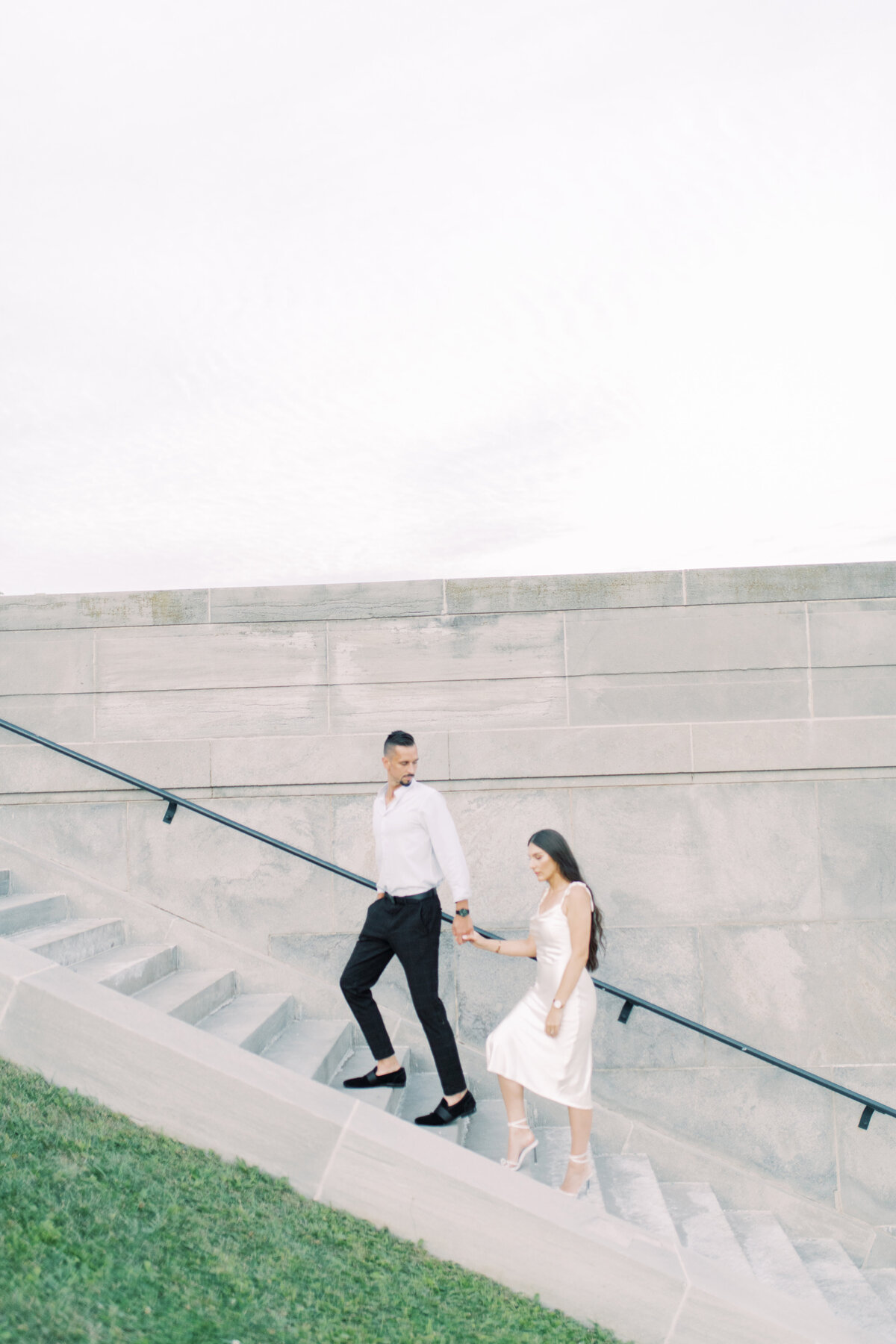 Engaged couple walking up the elegant stone steps of Toronto’s RC Harris Water  Treatment Plant, hand in hand, with a timeless, cinematic feel.