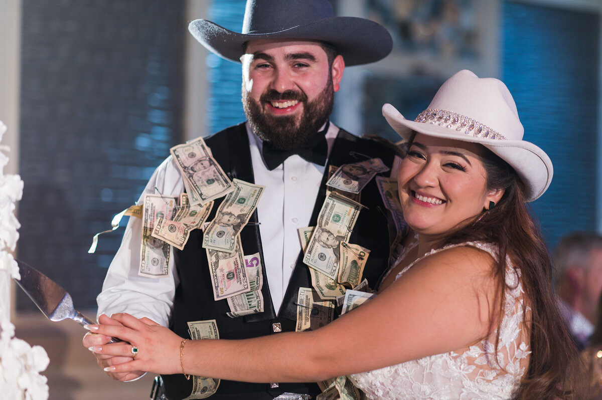 Wedding couple close-up dressed in money and starting the cake-cutting.