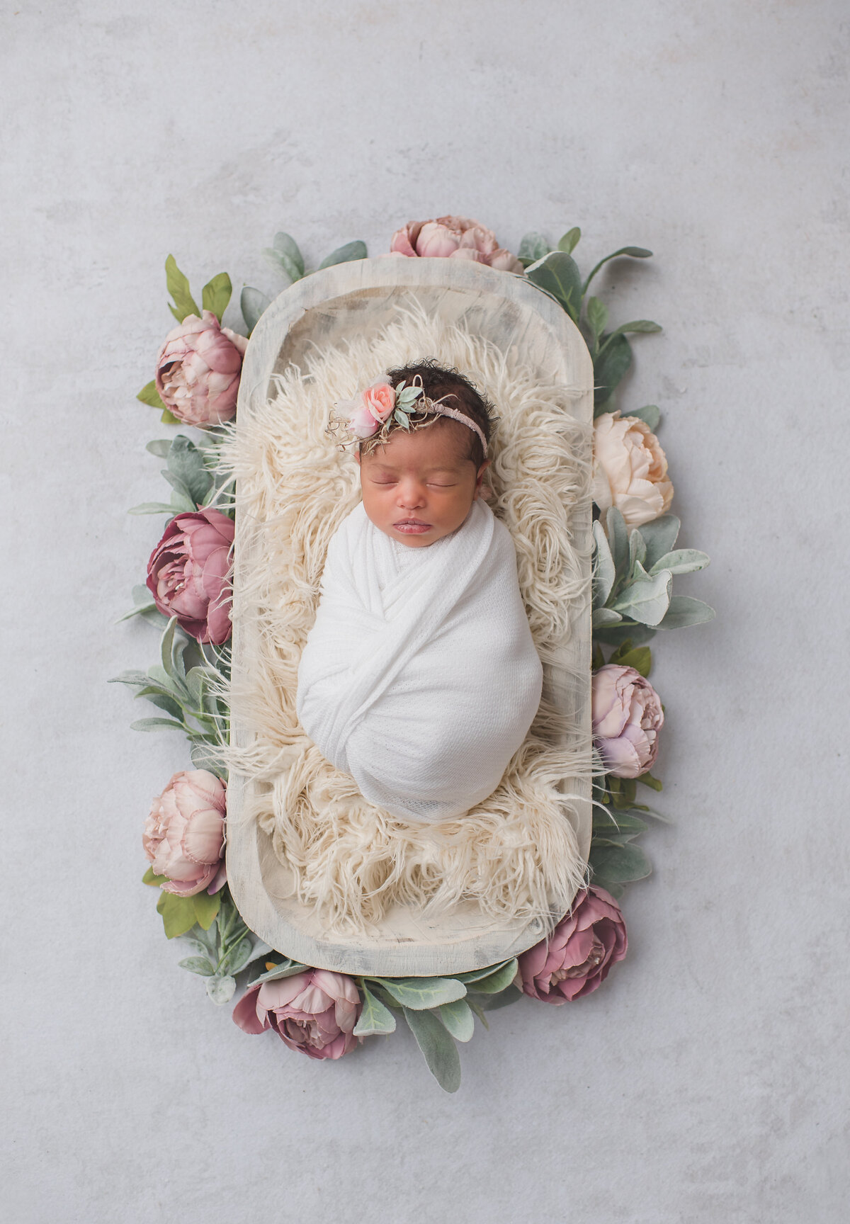 baby girl newborn session with roses around her and white backdrop