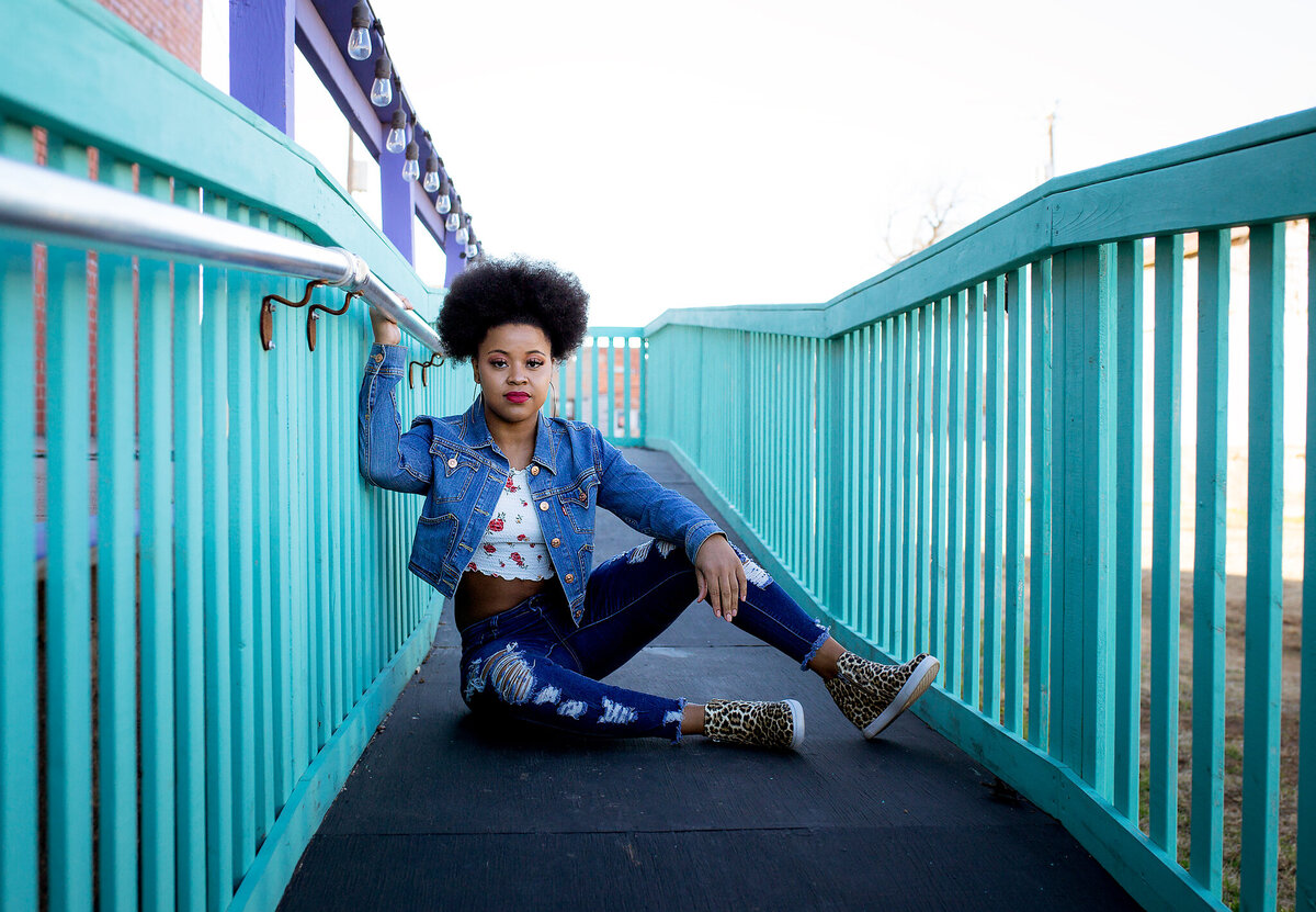 senior girl sitting on turquoise bridge