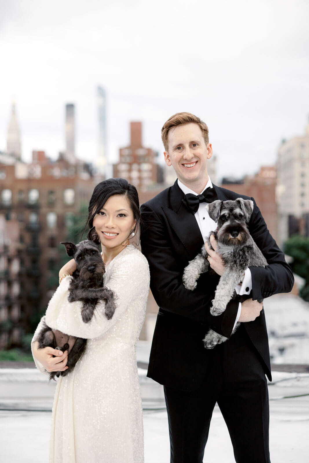 Close-up shot of the bride and groom carrying their dogs on a rooftop, in NYC. Image by Jenny Fu