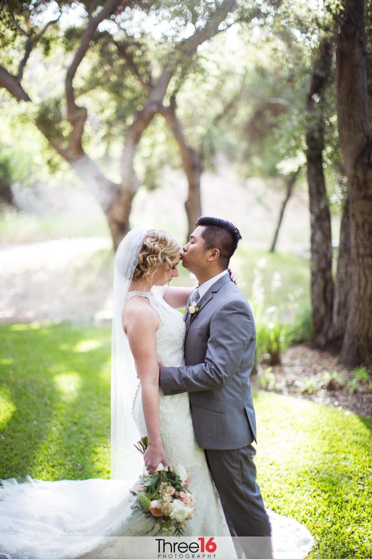 Groom kisses his Bride on the forehead in a sweet moment