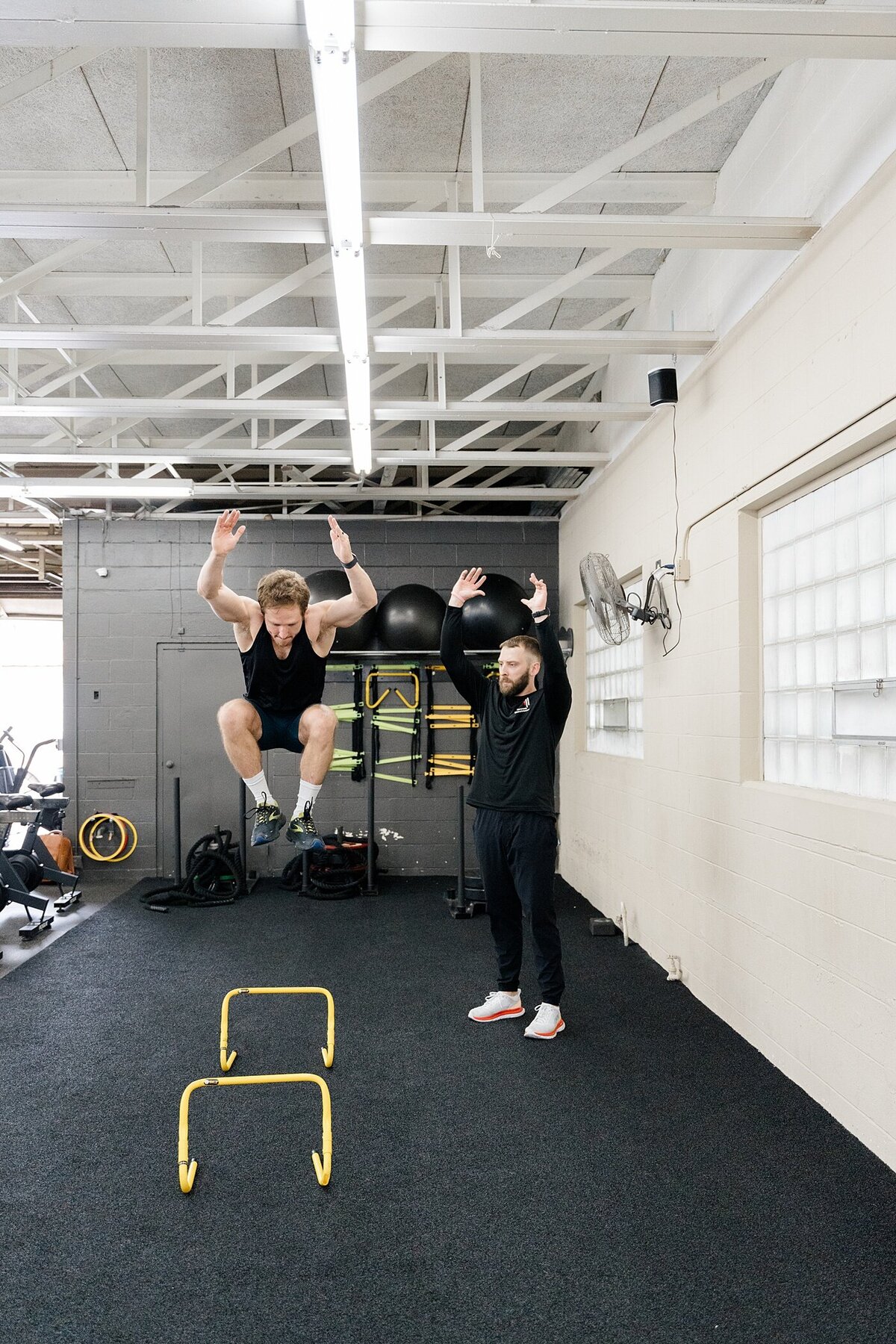 Columbus photographer captures training with woman jumping over hurdles with her personal trainer for candid brand photos