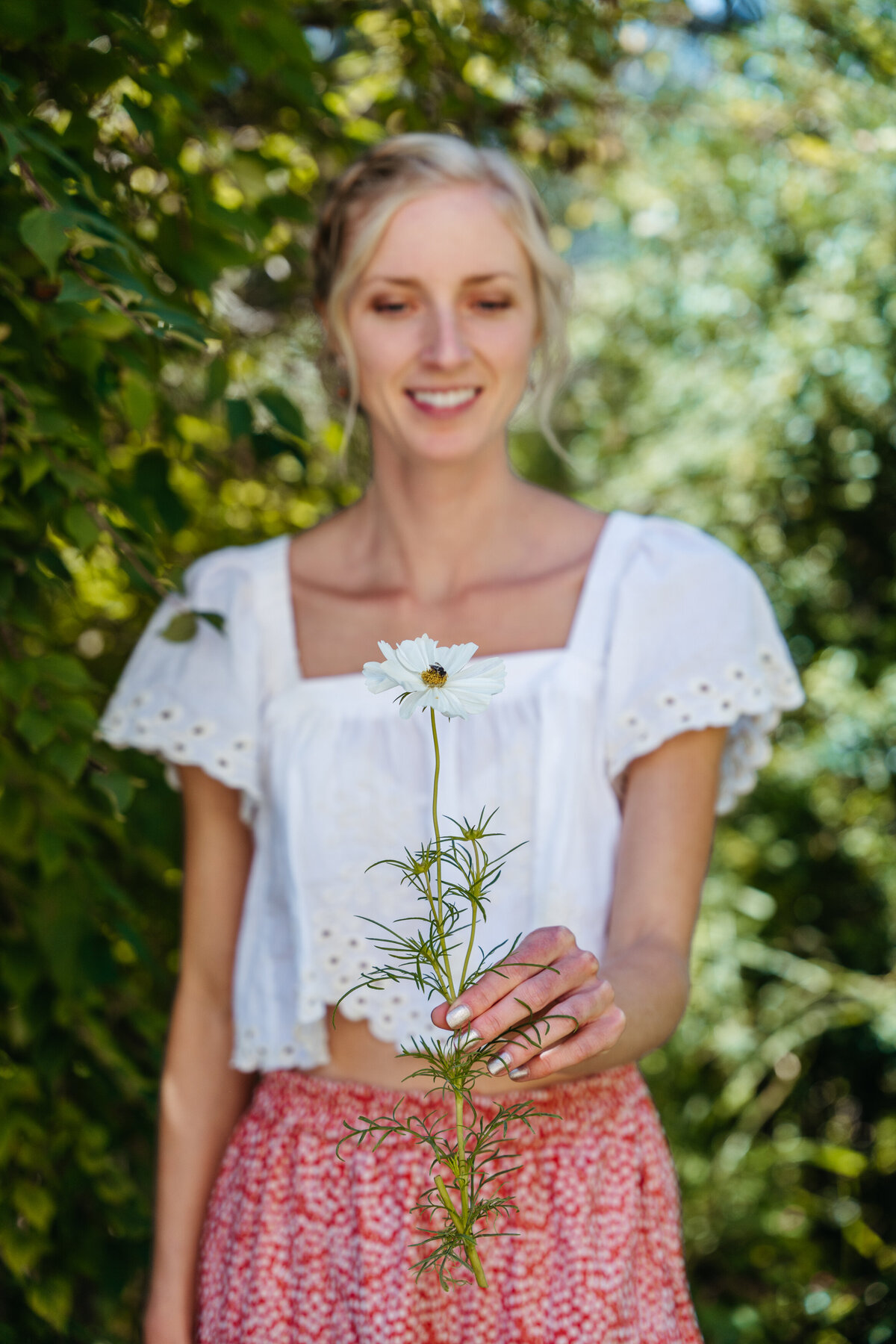Bride holding wildflower stem in hotel garden