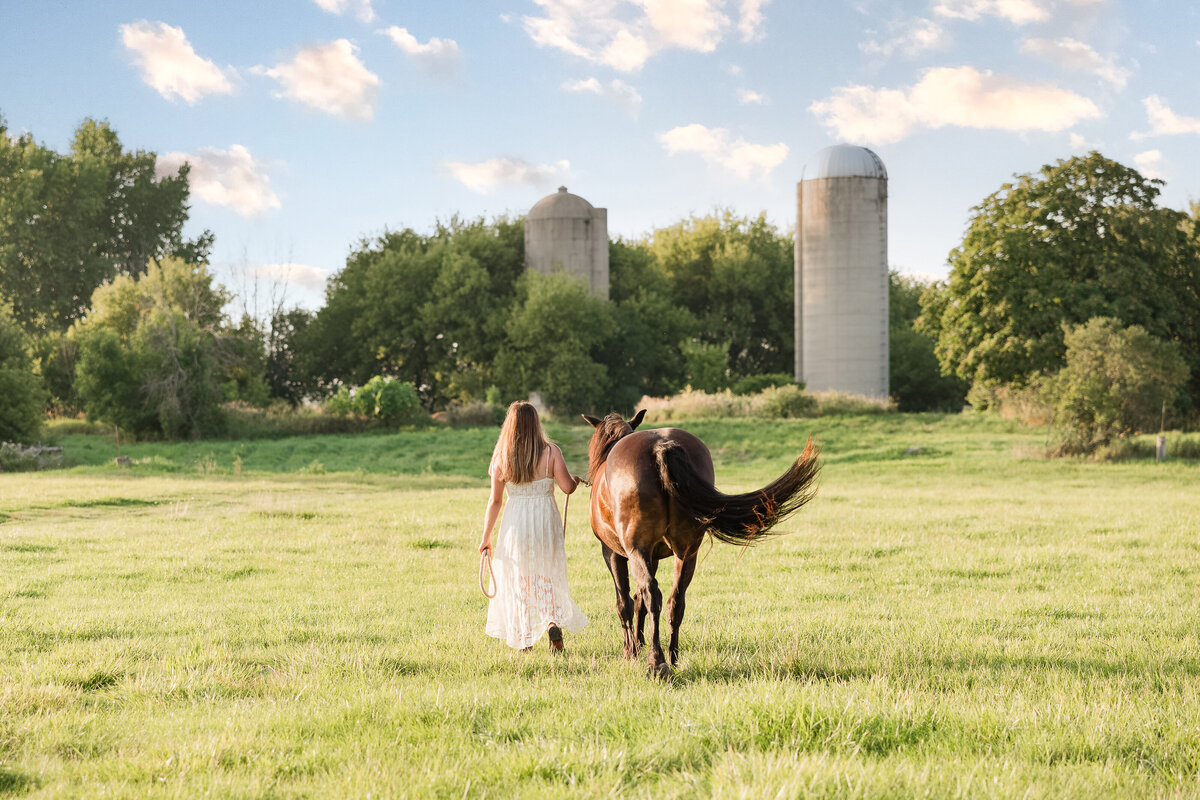 Senior girl walking away from the camera with her horse