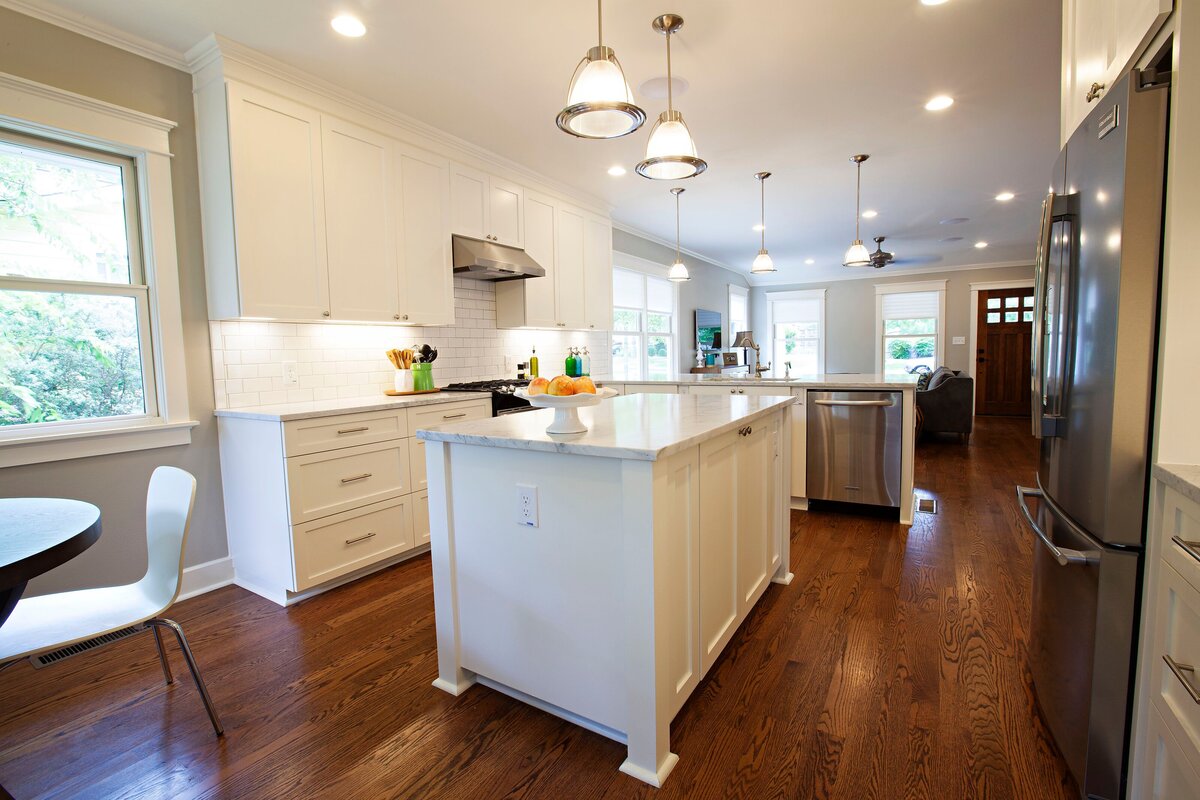 hardwood floors in kitchen with white island and grey kitchen appliances