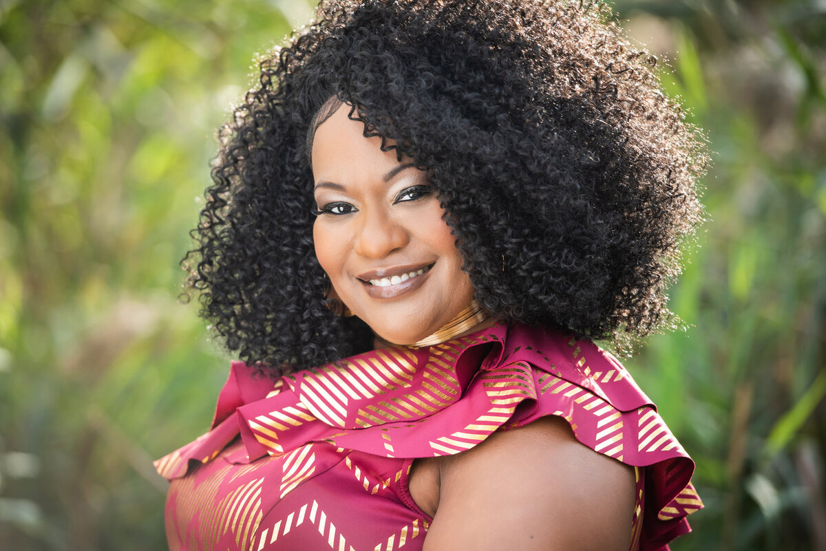 A woman smiling while standing in a garden area