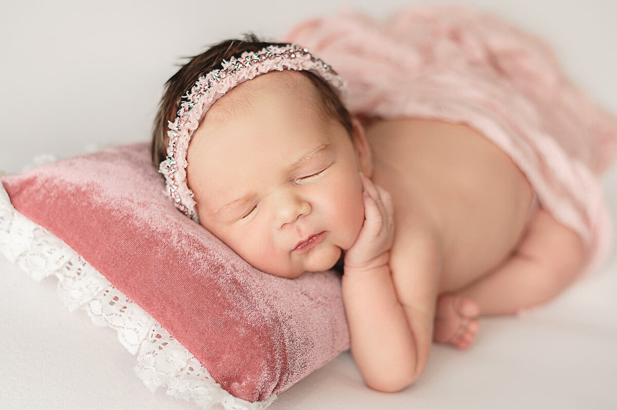 Baby girl sleeping on a white background in Greater Toronto Photography newborn studio on a pink pillow.