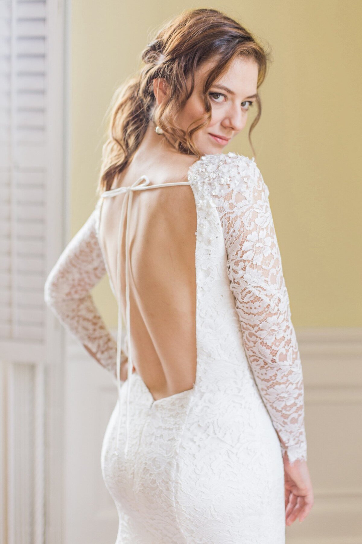 The low open back contrasts with the bateau neckline on this wedding dress style. A pair of ties at shoulder level tied into a bow keep the dress from sliding off the shoulders.