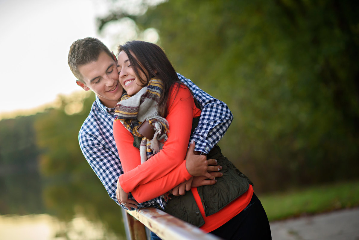 A man hugs his woman from behind during their engagement session.