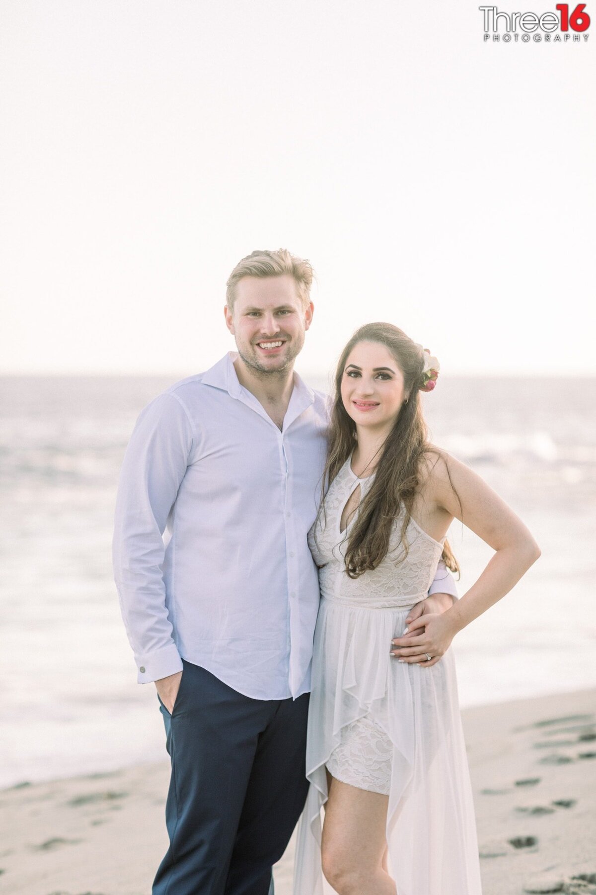 Newly married couple pose for photos after an elopement on the beach