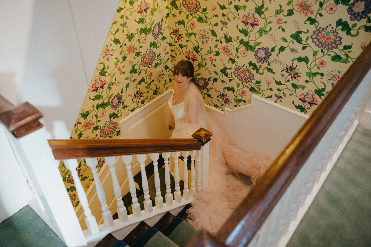 Bride in light pink robe walking down the stairs