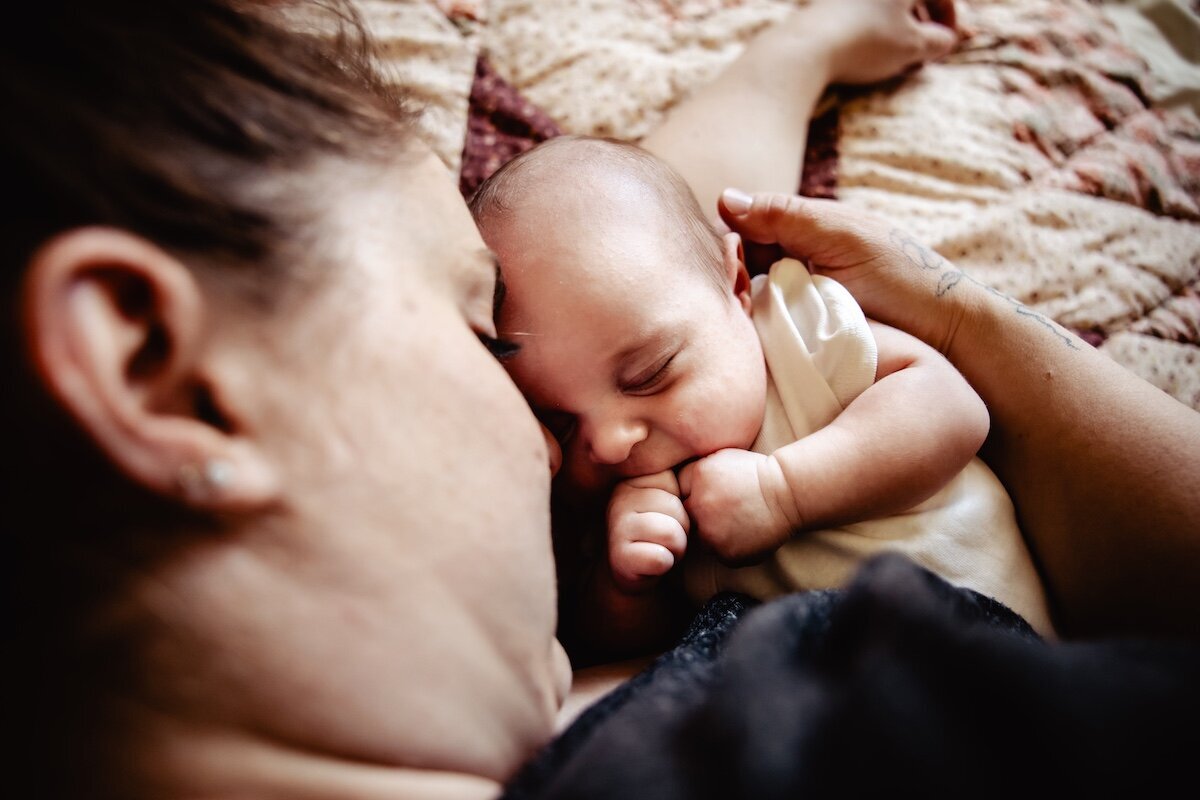a newborn baby girl fast asleep next to her mom