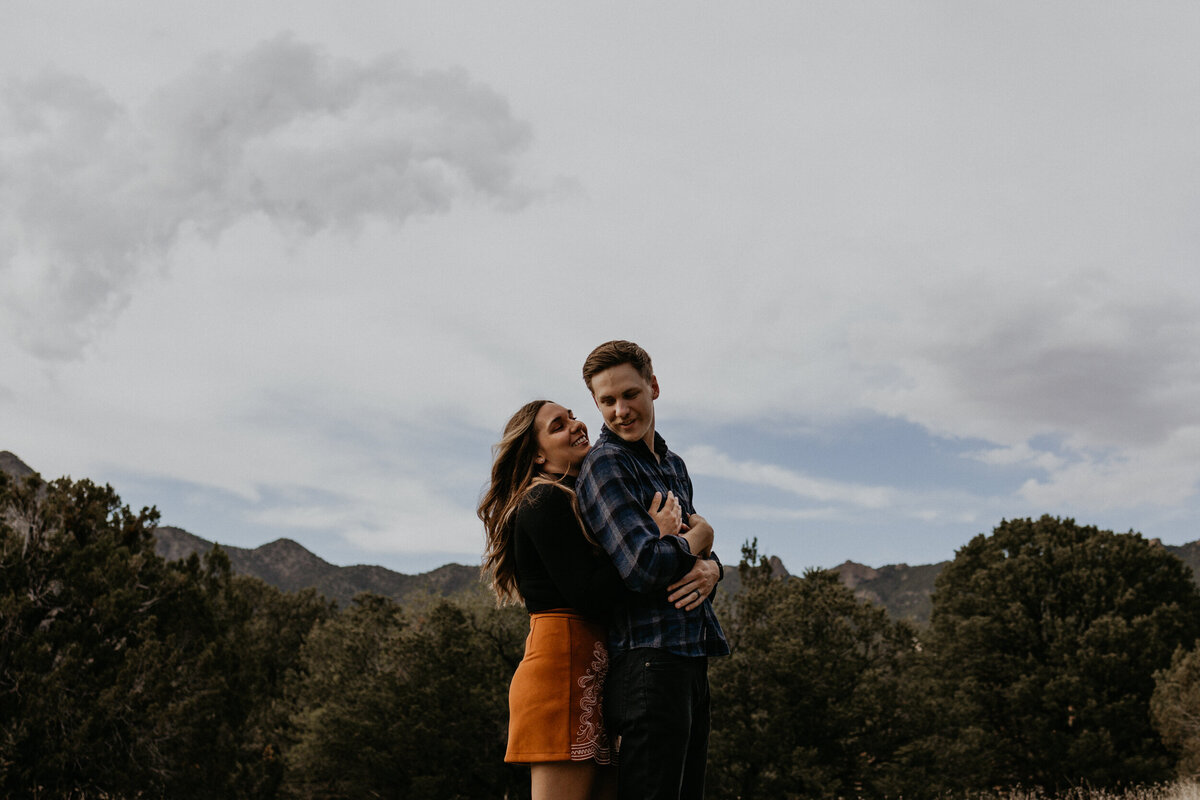 woman holding her fiancé from behind in the desert laughing