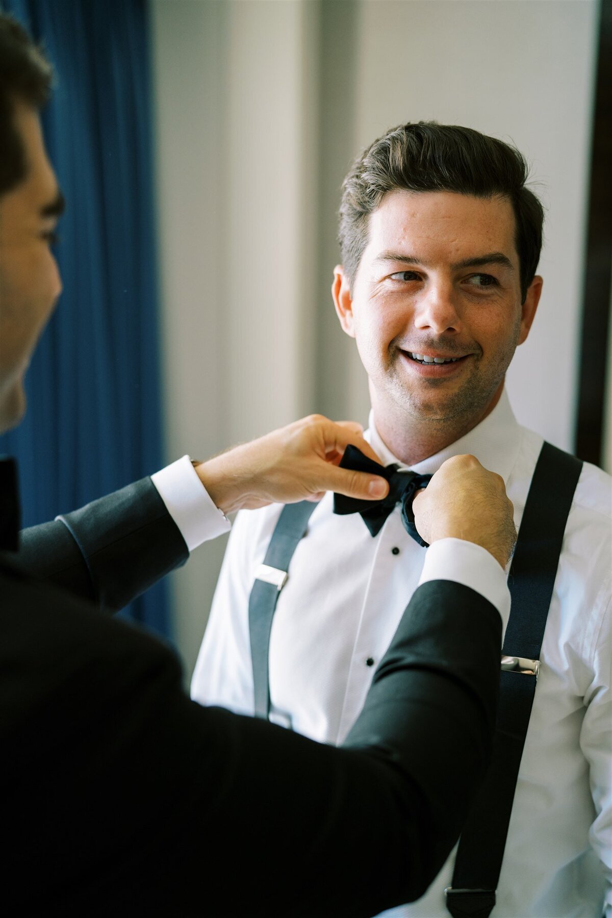 A close up of someone helping the groom with his tie. 