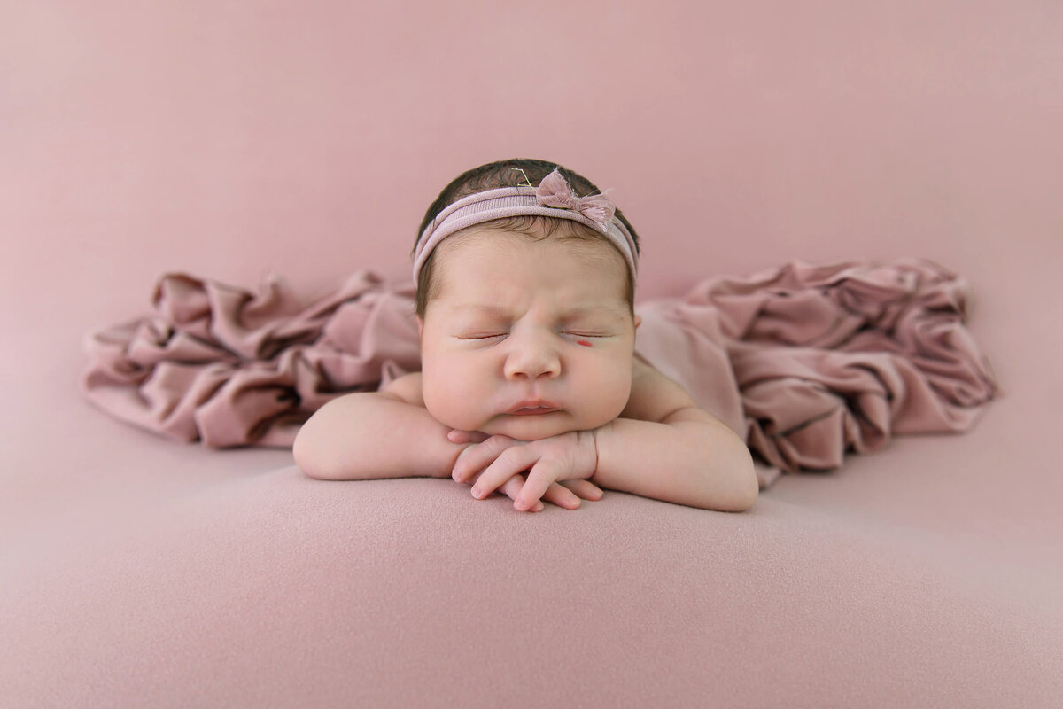 newborn girl on a pink background for her newborn photography session in Burlington, Ontario