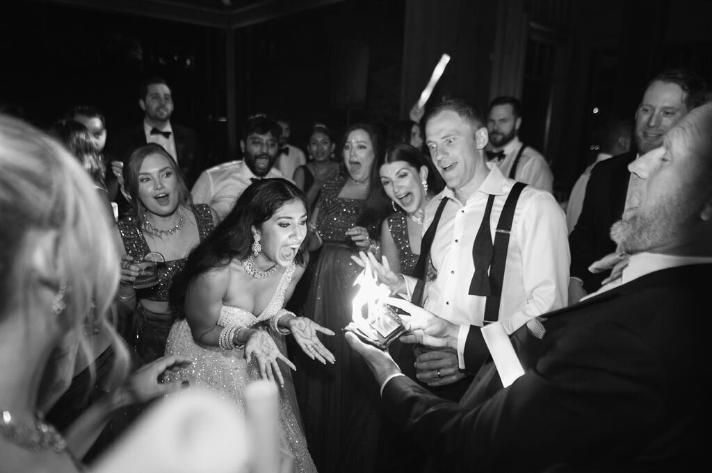 Bride, groom, and guests reacting excitedly to a fire magic trick during the wedding reception at Old Edwards Inn.