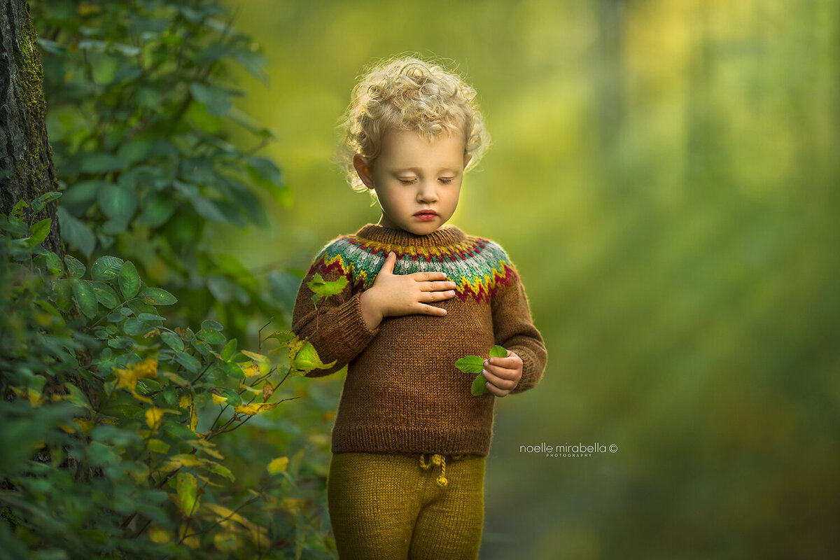 Child standing outside with hand over heart and eyes closed.