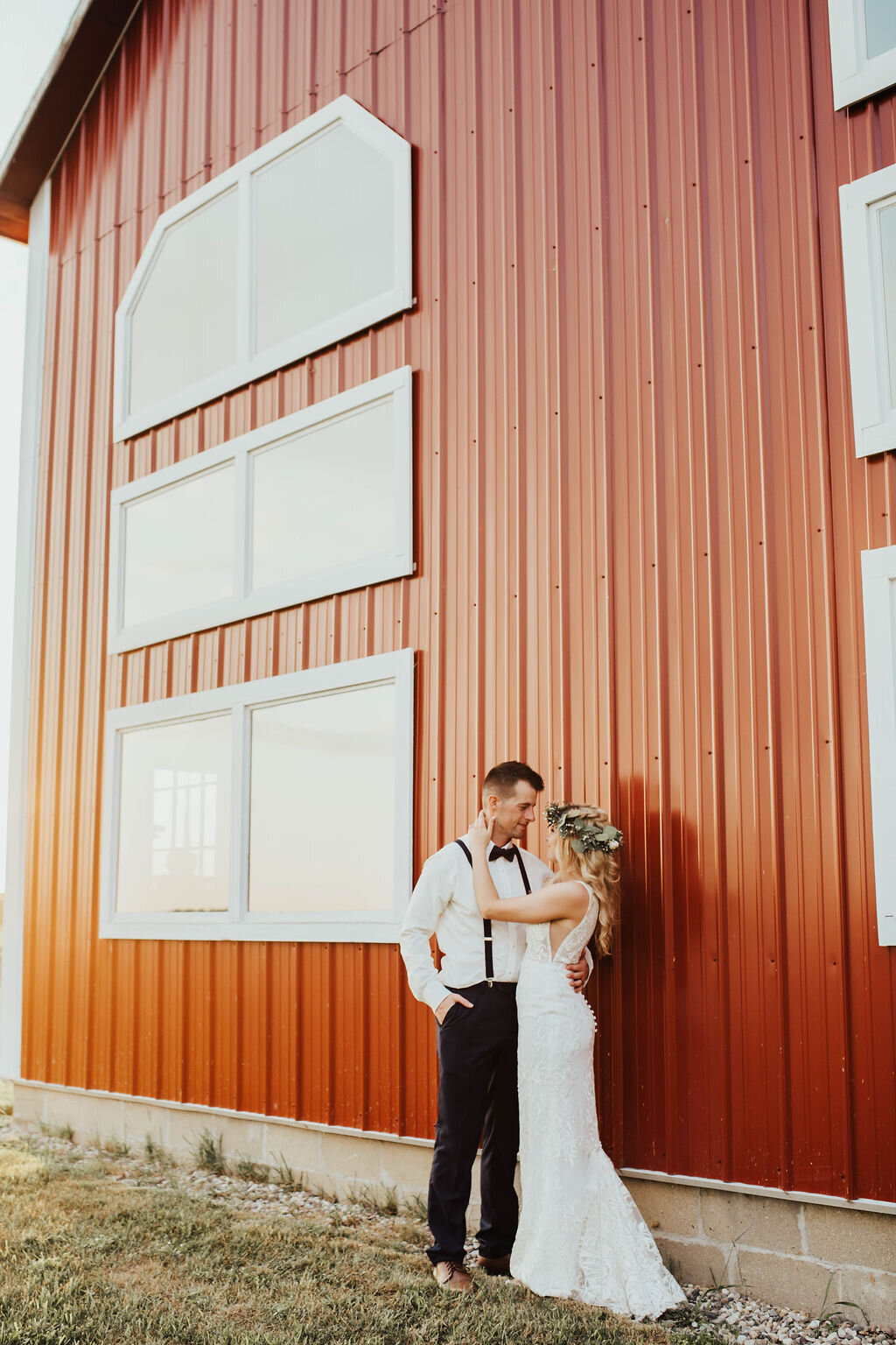 bride and groom posing in front of a red barn at their Michigan wedding