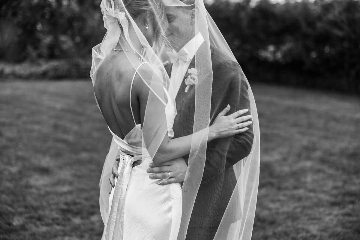 Bride and groom under the veil photo in black and white.