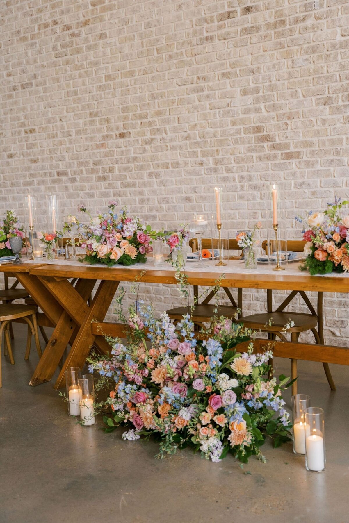 Romantic wedding reception table with pastel florals, taper candles, and whimsical garden-style arrangements.