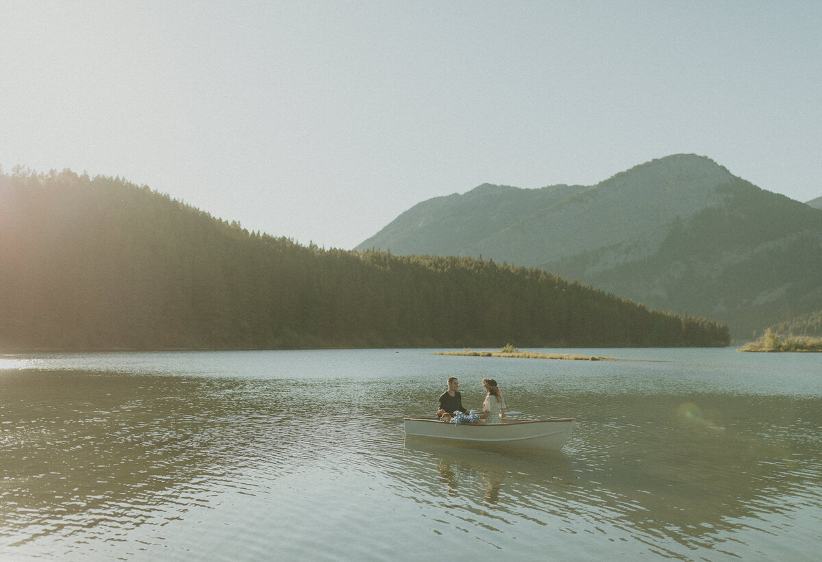 couple sitting in a row boat on a mountain lake