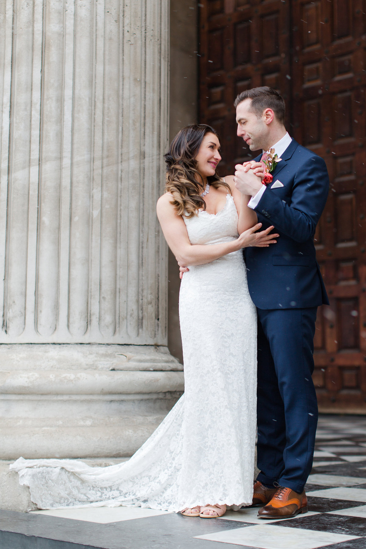Bride and groom hold hands and stare into each others eyes intimately at this snowy winter wedding at St Paul's cathedral in London