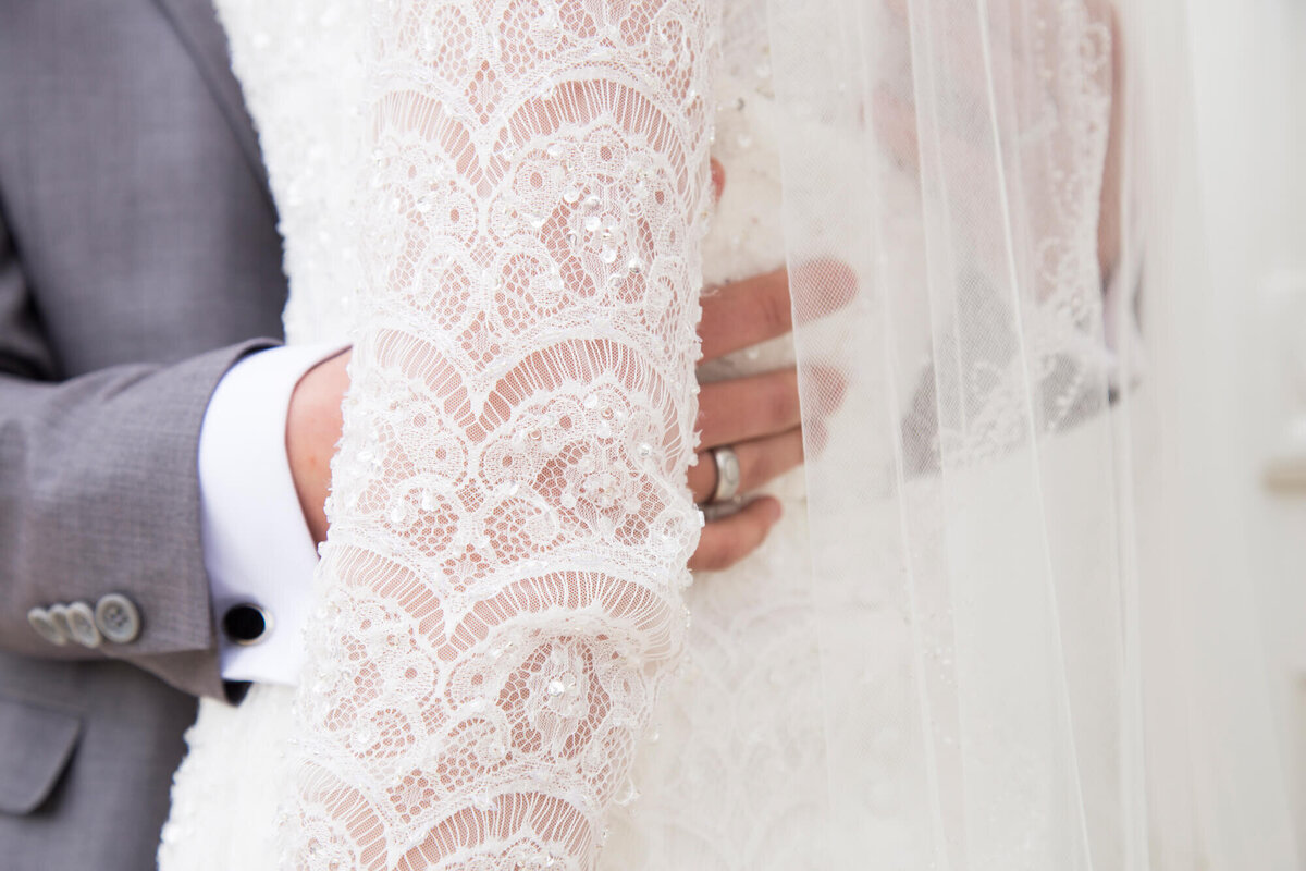 Groom's hands lovingly wrapping around  bride's waist on bright wedding day