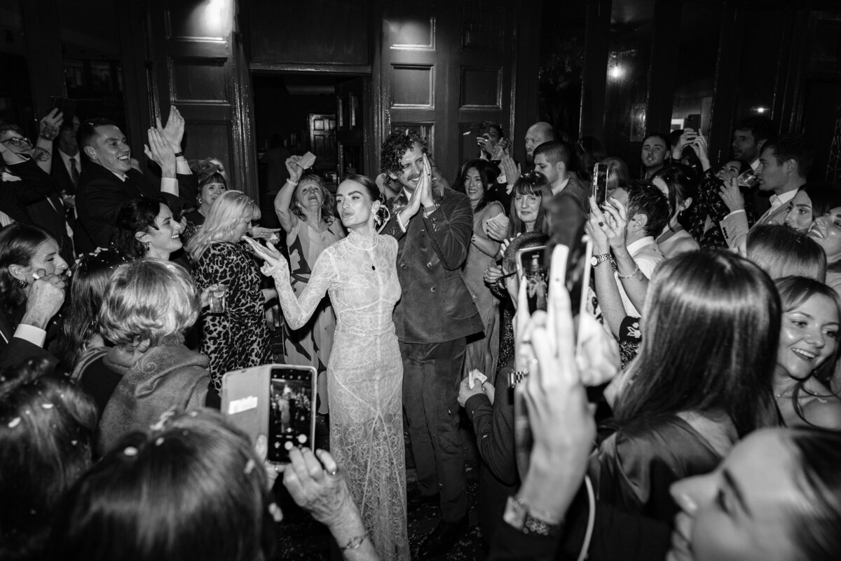 couple celebrate with all of their friends and family around them after a confetti toss at their central london wedding