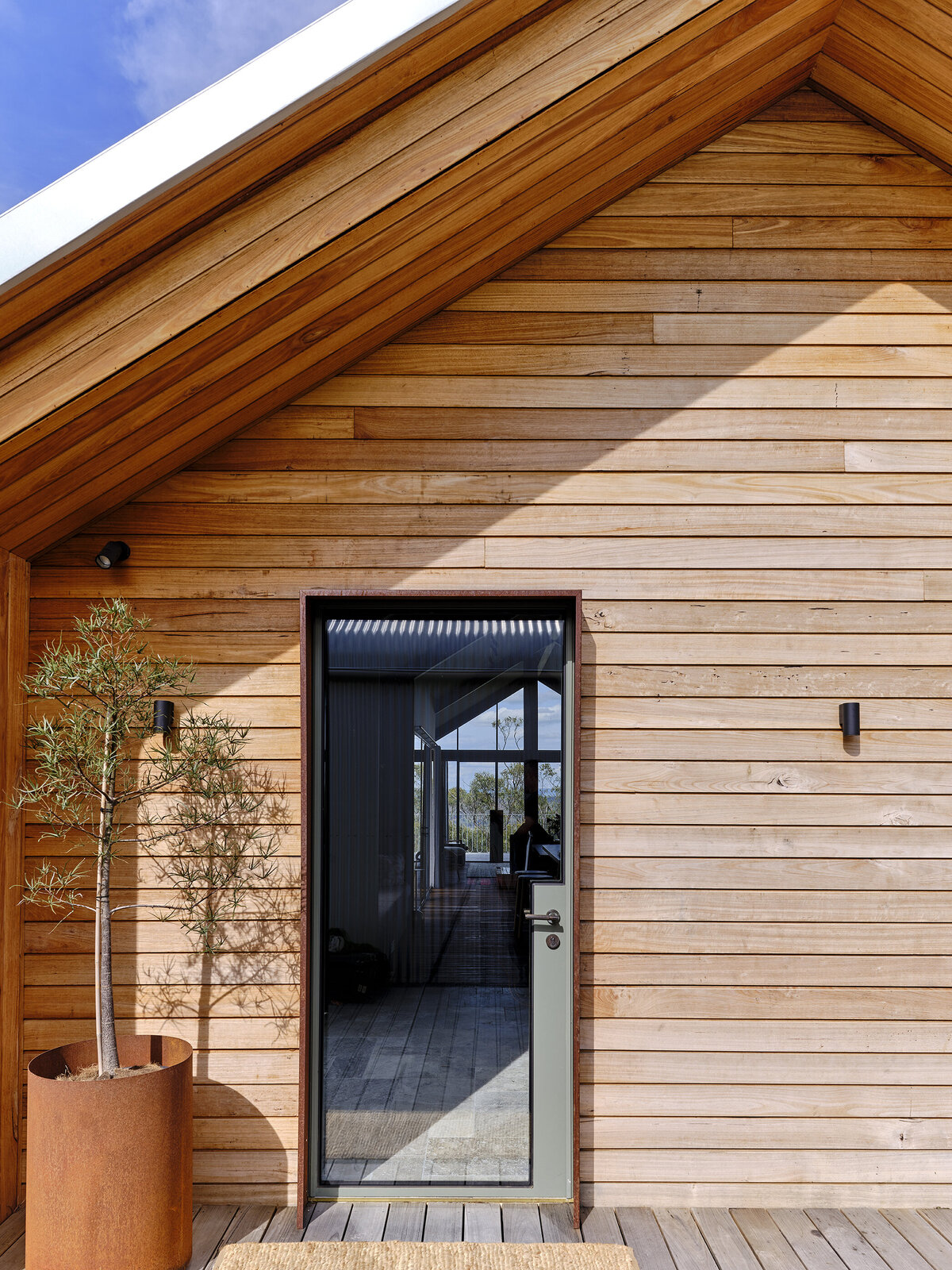 Timber-clad modern country home entry door with rusted pot planter, designed by interior stylist Lisa Hunter in Strathcreek.